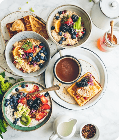 Beautiful arrangement of healthy breakfast bowls with berries, nuts, and pancakes